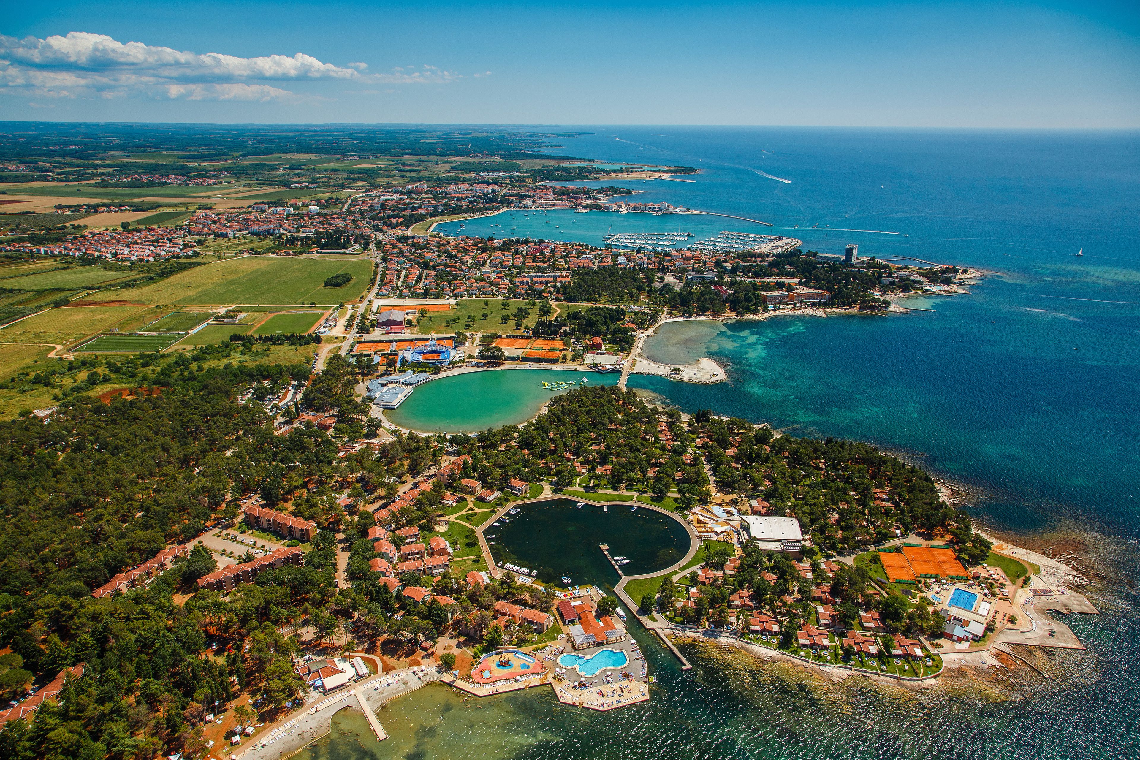 An aerial view of a coastal resort with a marina, swimming areas, and residential buildings.