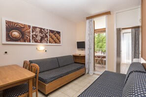A compact room with a sofa, a dining table, and a TV.