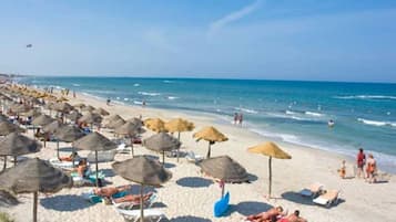 En privat strand, hvidt sand, liggestole, parasoller