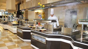 A buffet setup with multiple serving stations, a checkered floor, and a chef preparing food. - El Mouradi Gammarth (La Marsa)