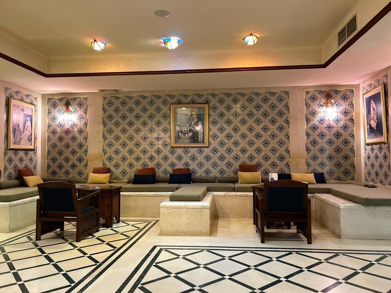 A lounge area with patterned wallpaper, cushioned seating, and a geometric patterned rug.