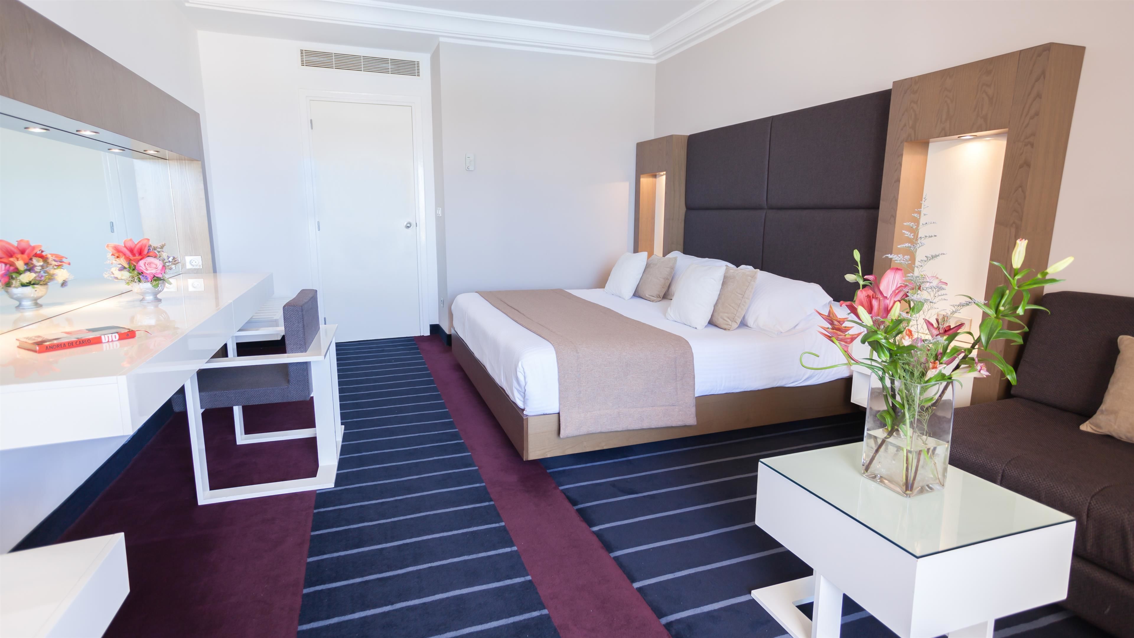 A hotel room with a bed, a desk, a sofa, and a coffee table.