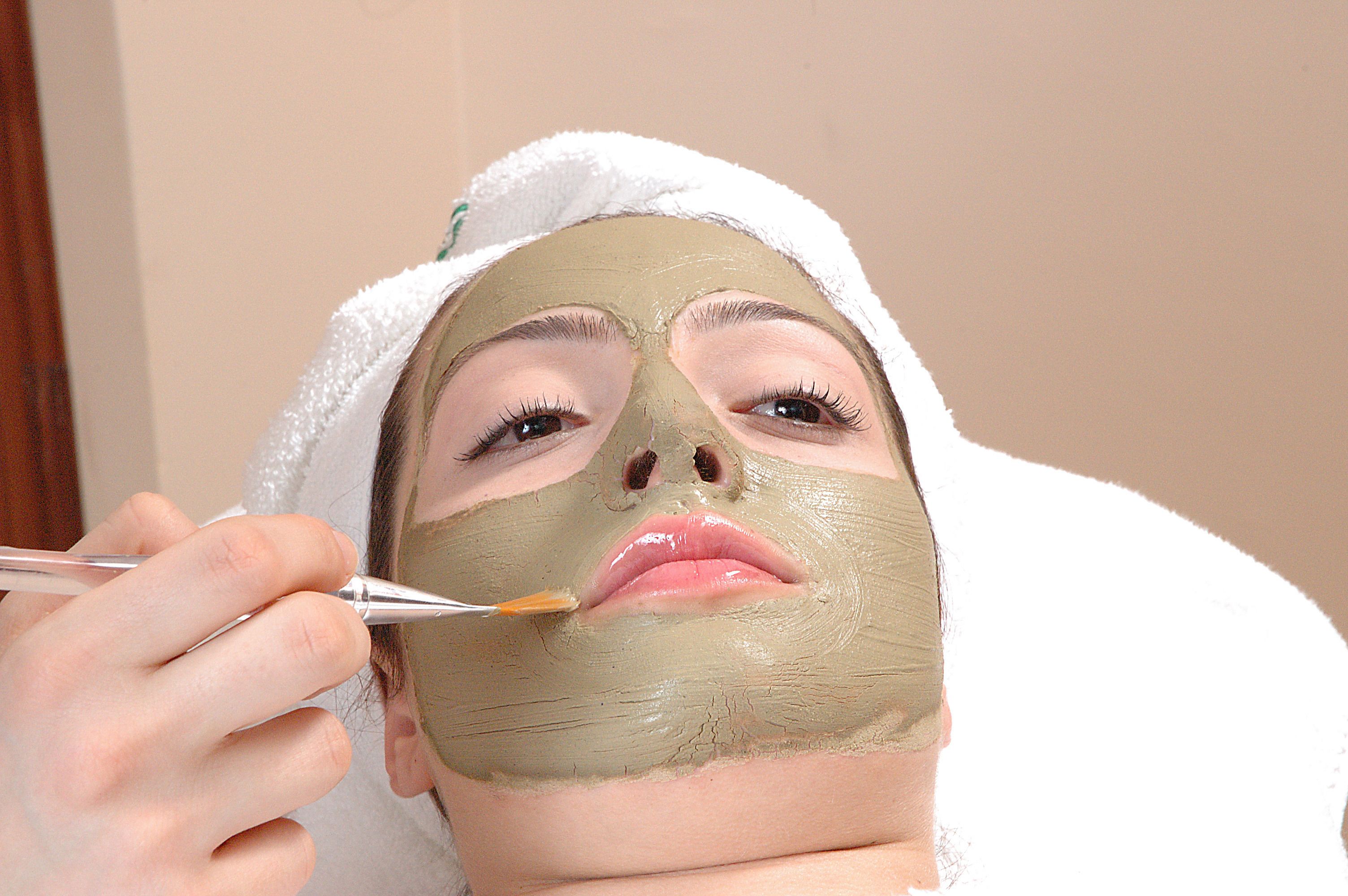 A person receiving a facial treatment with a towel on their head.