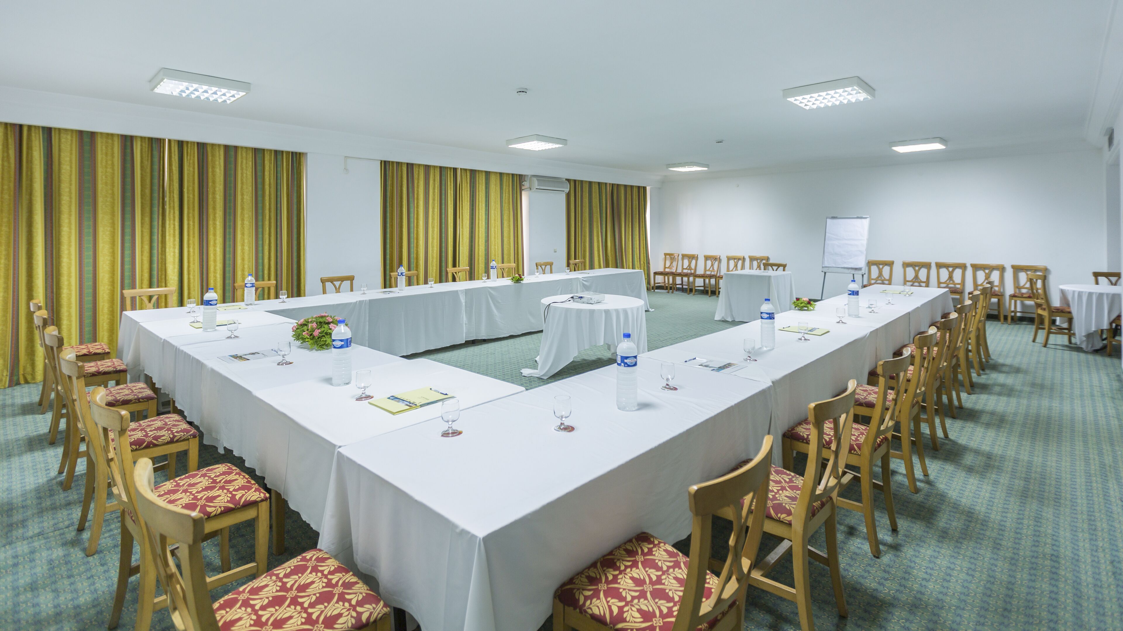 Un salón de conferencias con una larga mesa, sillas y una pizarra.