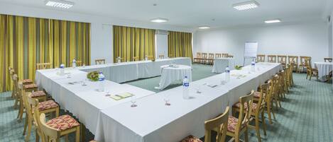 Un salón de conferencias con una larga mesa, sillas y una pizarra.