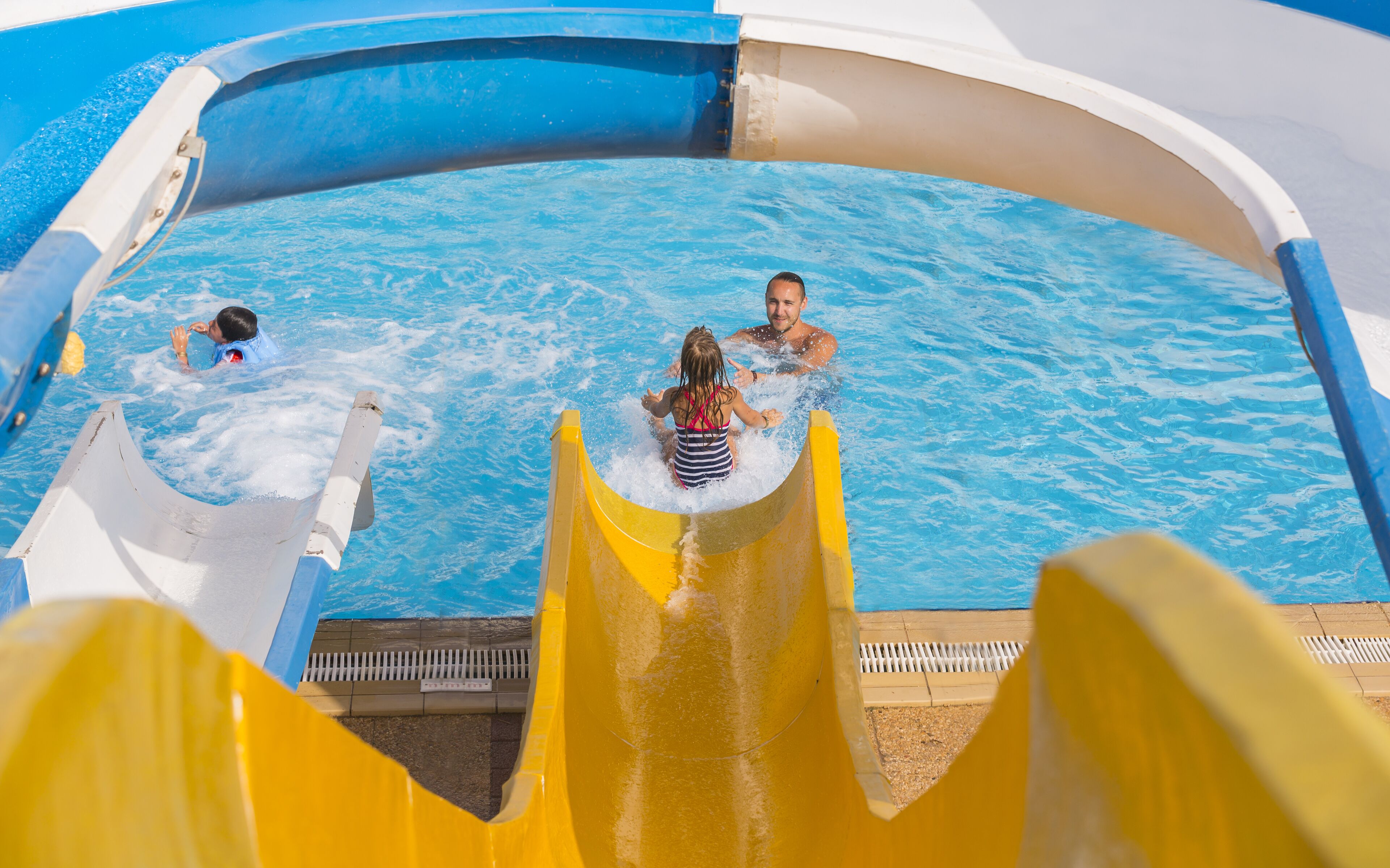 Una piscina con un tobogán amarillo y una persona dentro.