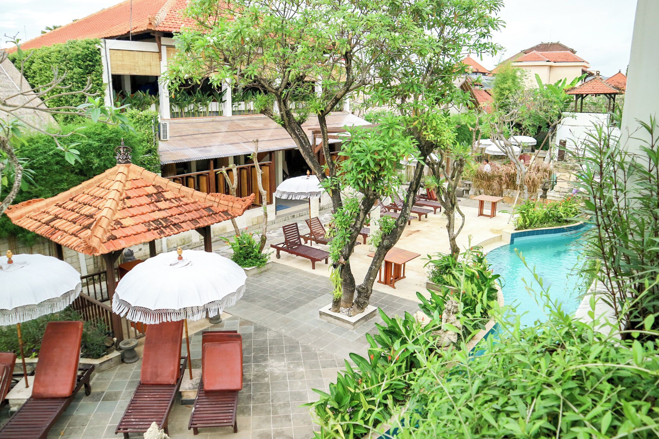 A poolside area with lounge chairs, umbrellas, and a swimming pool.