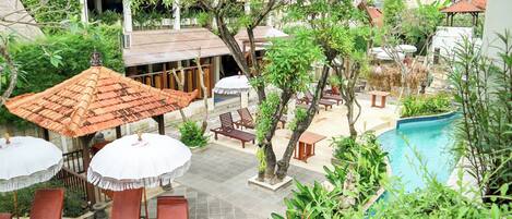 A poolside area with lounge chairs, umbrellas, and a swimming pool.