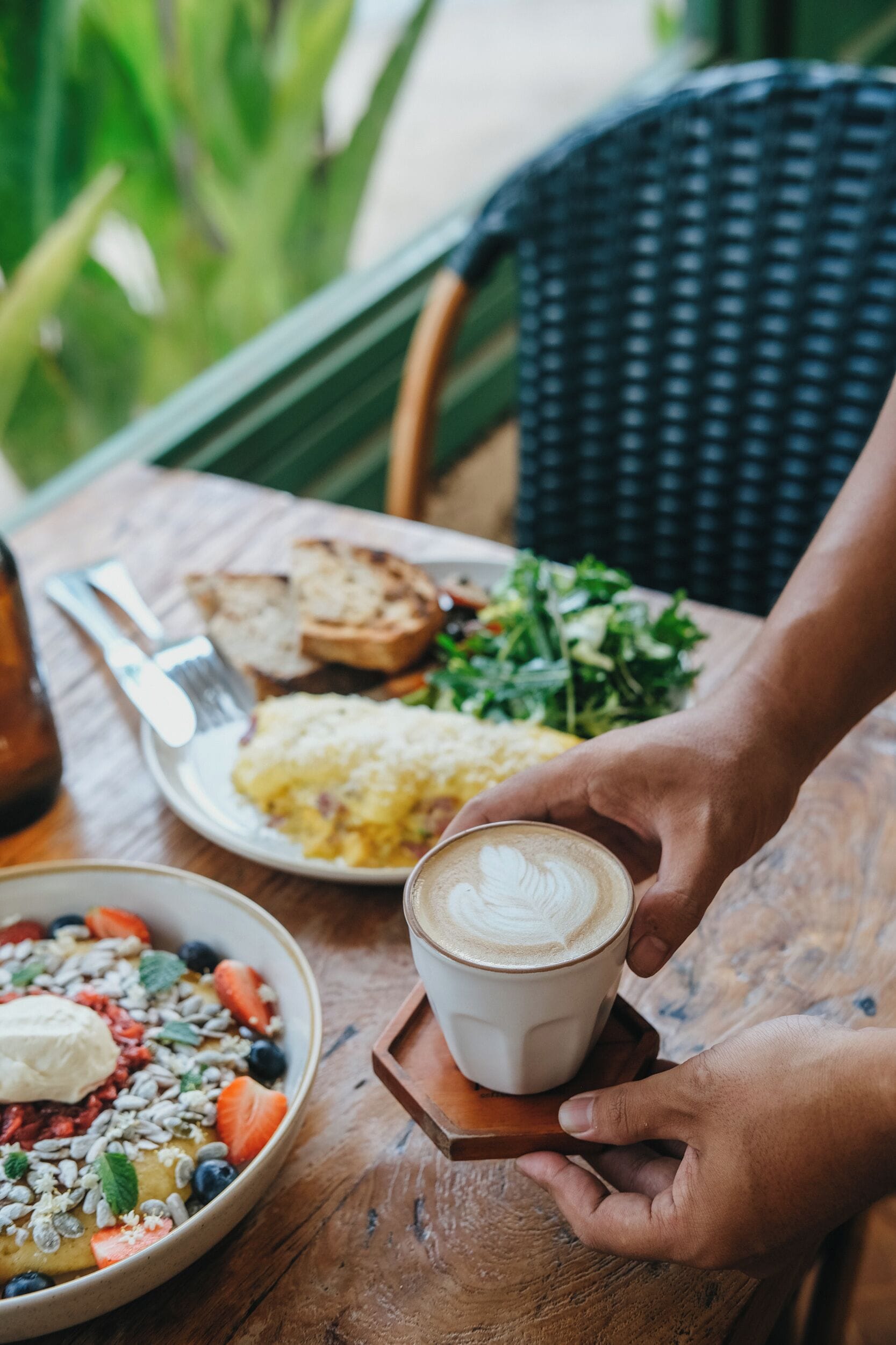Une table en bois, mise pour le petit-déjeuner, avec des toasts, des œufs brouillés et une tasse de café.