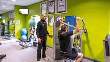 A gym with exercise equipment, a television, and framed sports memorabilia on the wall.