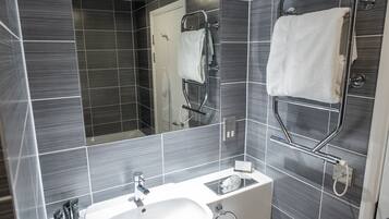 A modern bathroom with a white sink, mirror, and towel rack.
