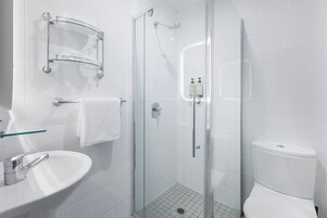 A modern bathroom with a glass-enclosed shower, a white sink, and a toilet.