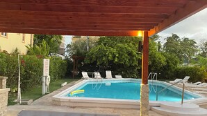 A swimming pool with lounge chairs and a covered area. - The Monteray Hotel (St. Lawrence Gap)