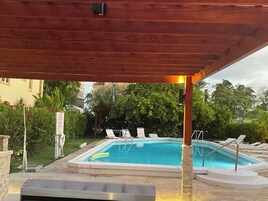 Una piscina al aire libre, sillones reclinables de piscina