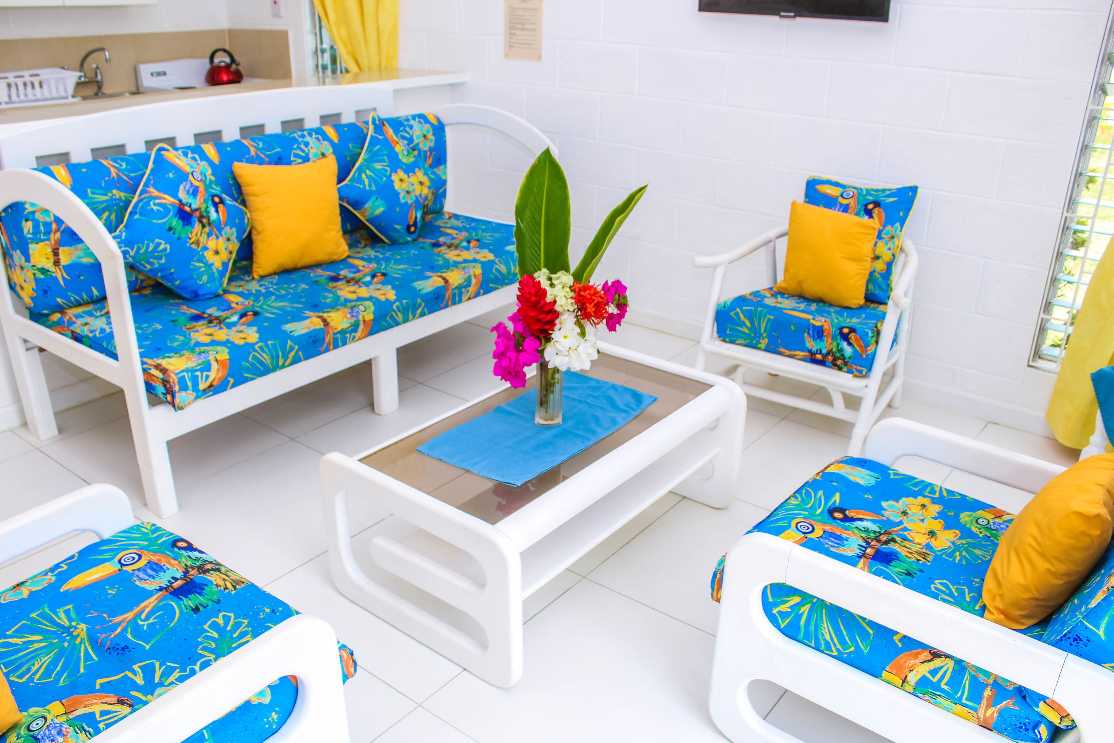 A bright room with a white sofa and chairs, a small table, and a vase with flowers.