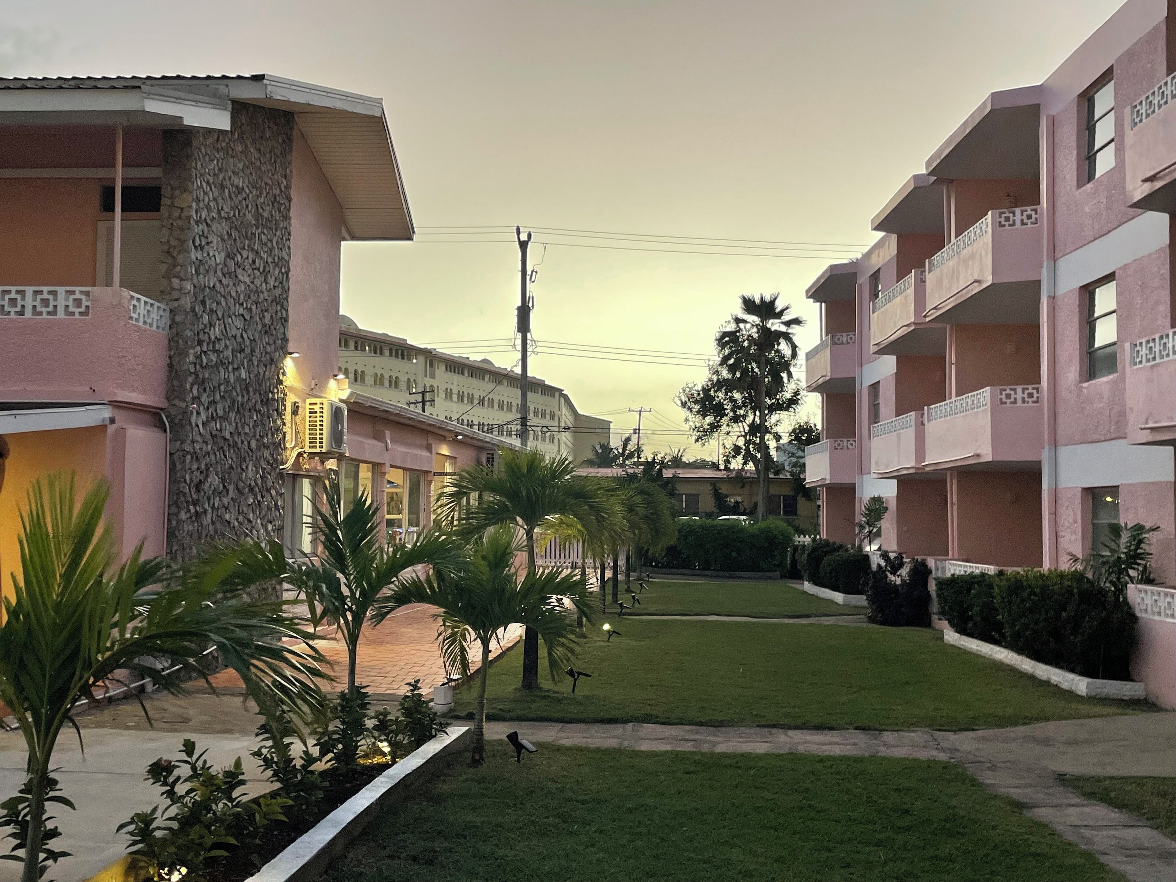 A residential building with balconies, a paved courtyard, and a stone wall.