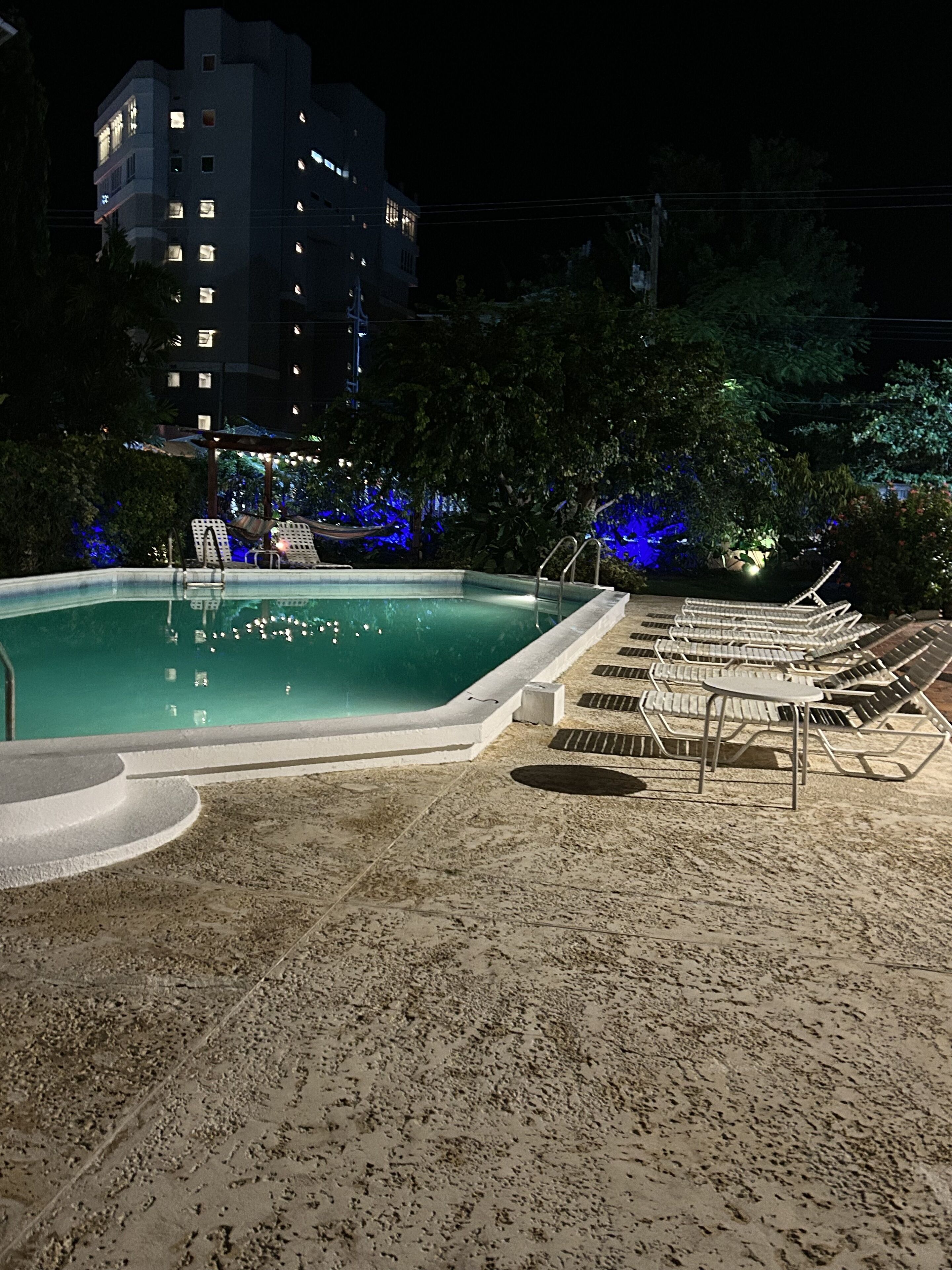 Une piscine nocturne dotée de chaises longues et d’une terrasse carrelée.