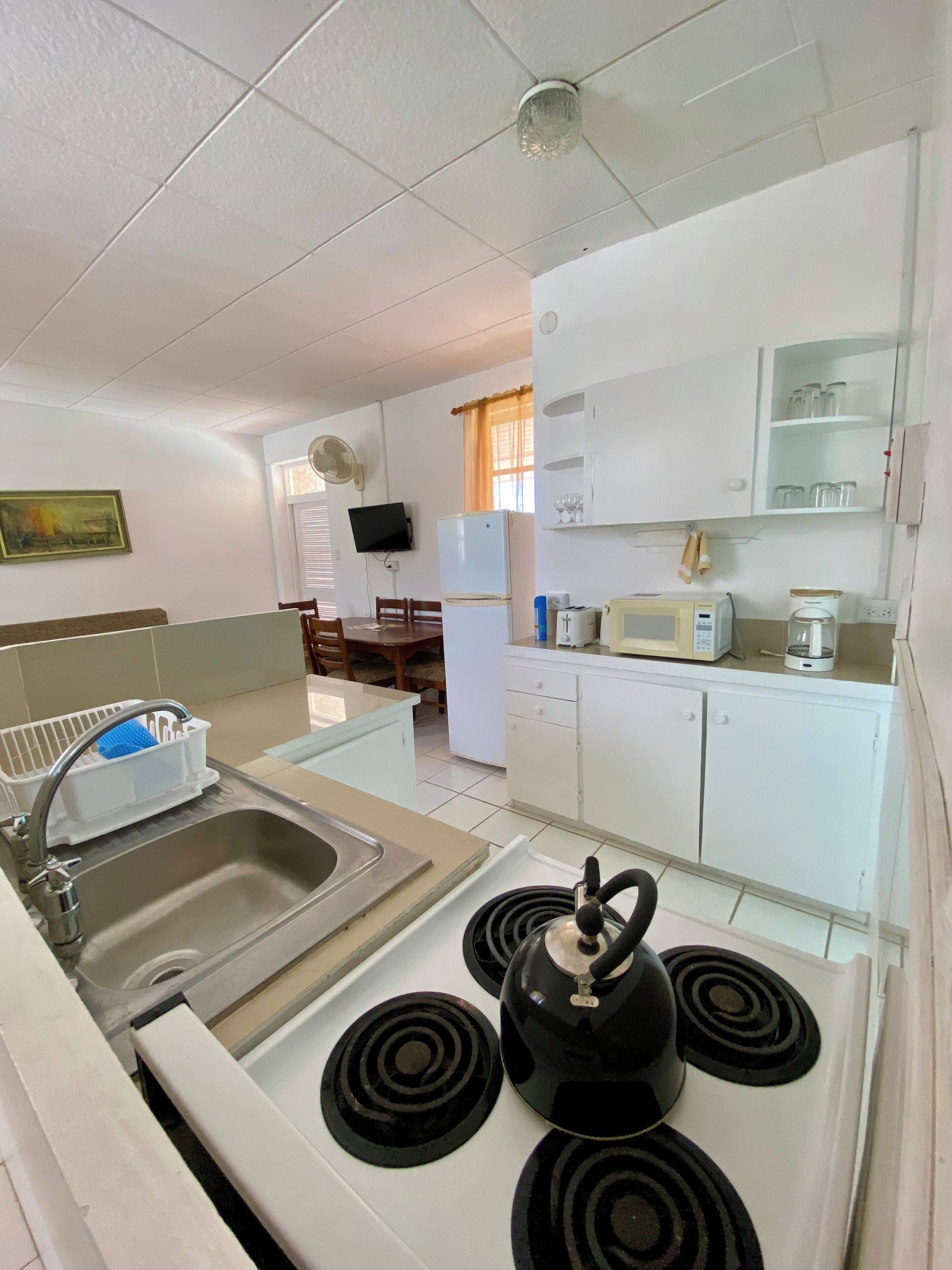 Una cocina compacta con fregadero, estufa, microondas y refrigerador.