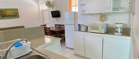 Una cocina compacta con fregadero, estufa, microondas y refrigerador.