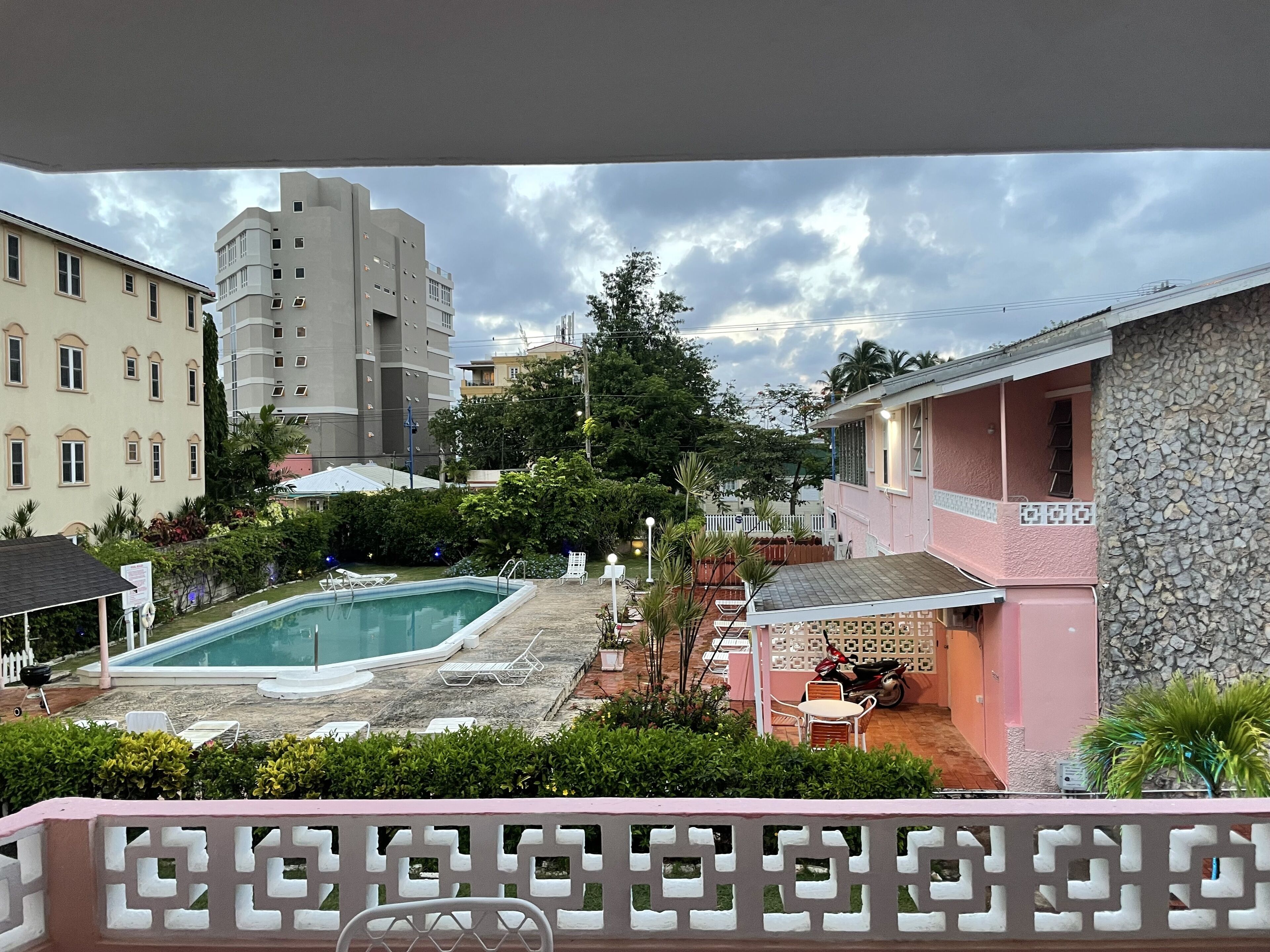 Ein Wohngebiet mit einem Schwimmbad, einem rosa Haus und einem hohen Gebäude im Hintergrund.