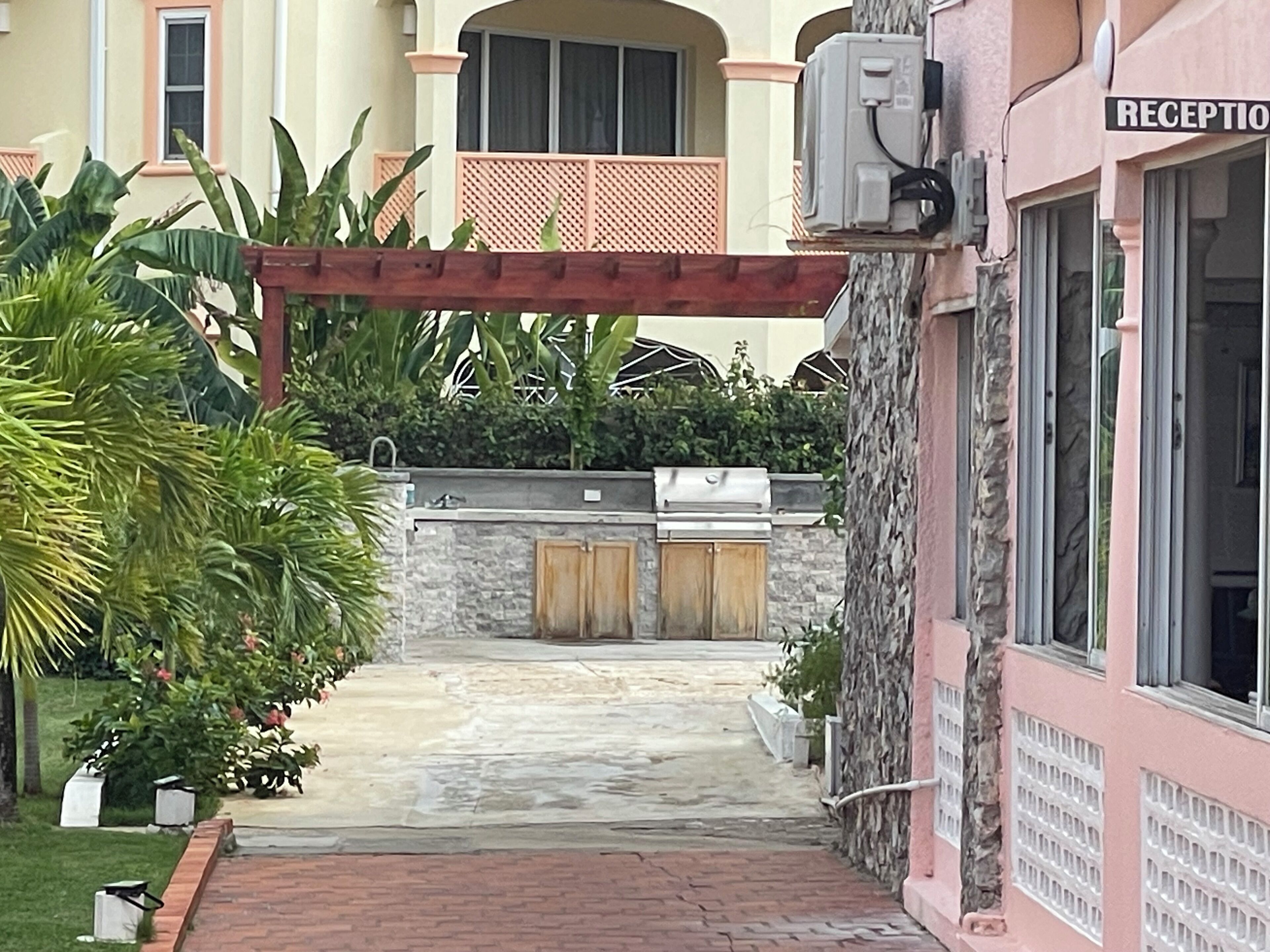 Un espace d’accueil avec un mur en pierre, un barbecue et une allée couverte.