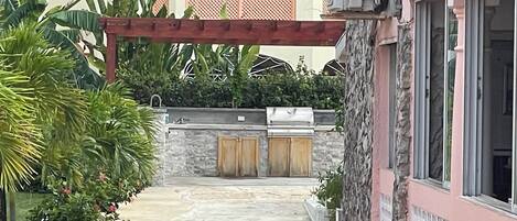 Un espace d’accueil avec un mur en pierre, un barbecue et une allée couverte.