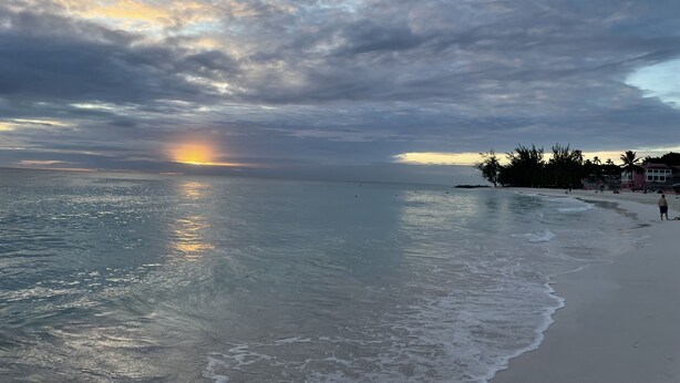 A beach with a sunset, calm sea, and a row of houses along the shore. - The Monteray Hotel (St. Lawrence Gap)
