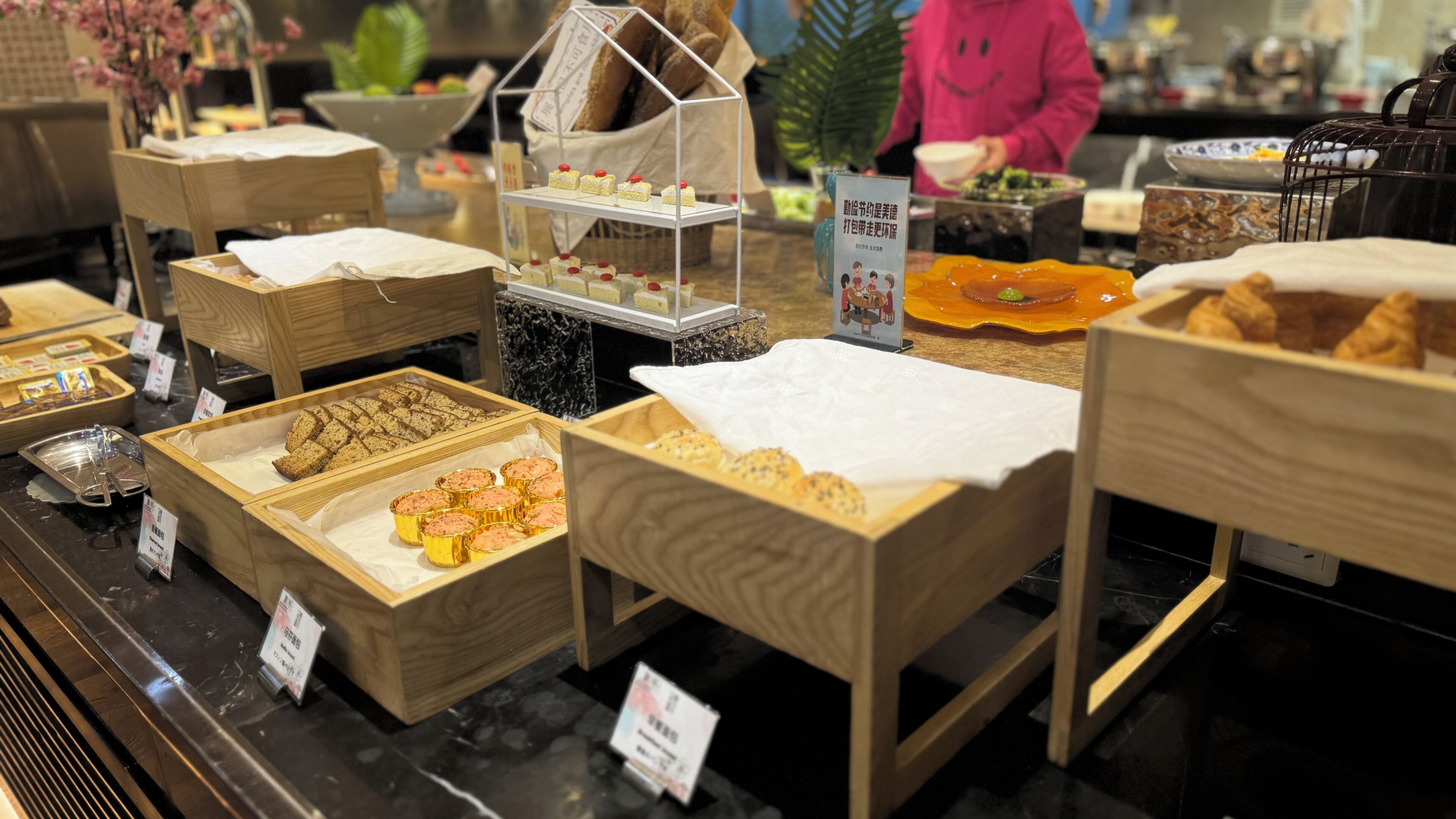 A bakery display with various baked goods in wooden boxes and trays.