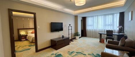 A hotel room with a large bed, a TV, a desk, and a sofa.