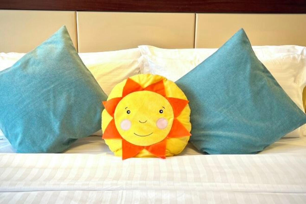 Una cama con dos almohadas y una almohada con forma de sol.