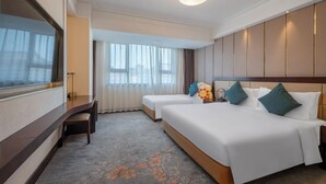 Een hotelkamer met een groot bed, een kleiner bed, een bureau en een groot raam.