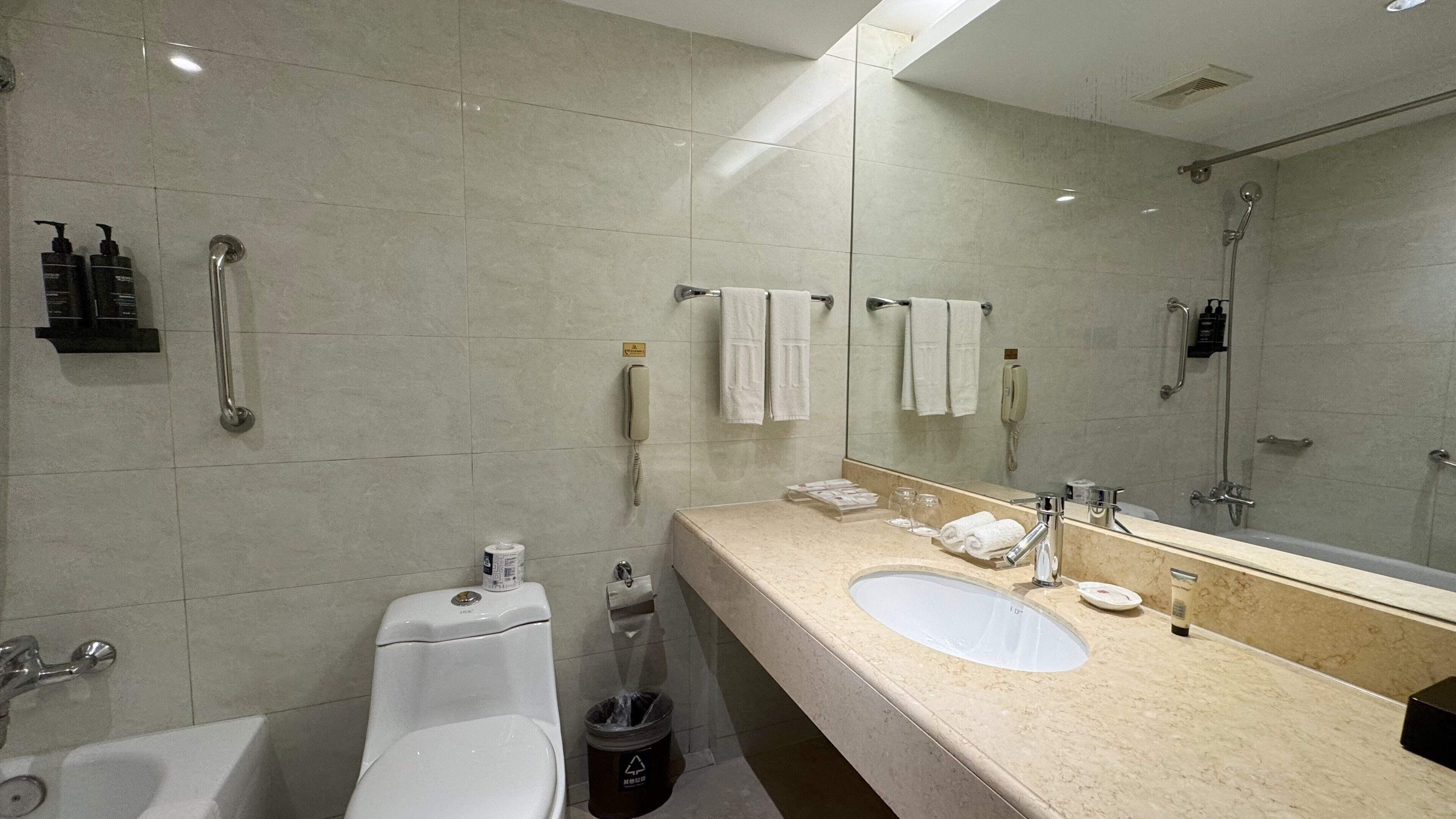 Moderni kylpyhuone, jossa on kaksi pesuallasta, wc, suihku ja suuri peili.