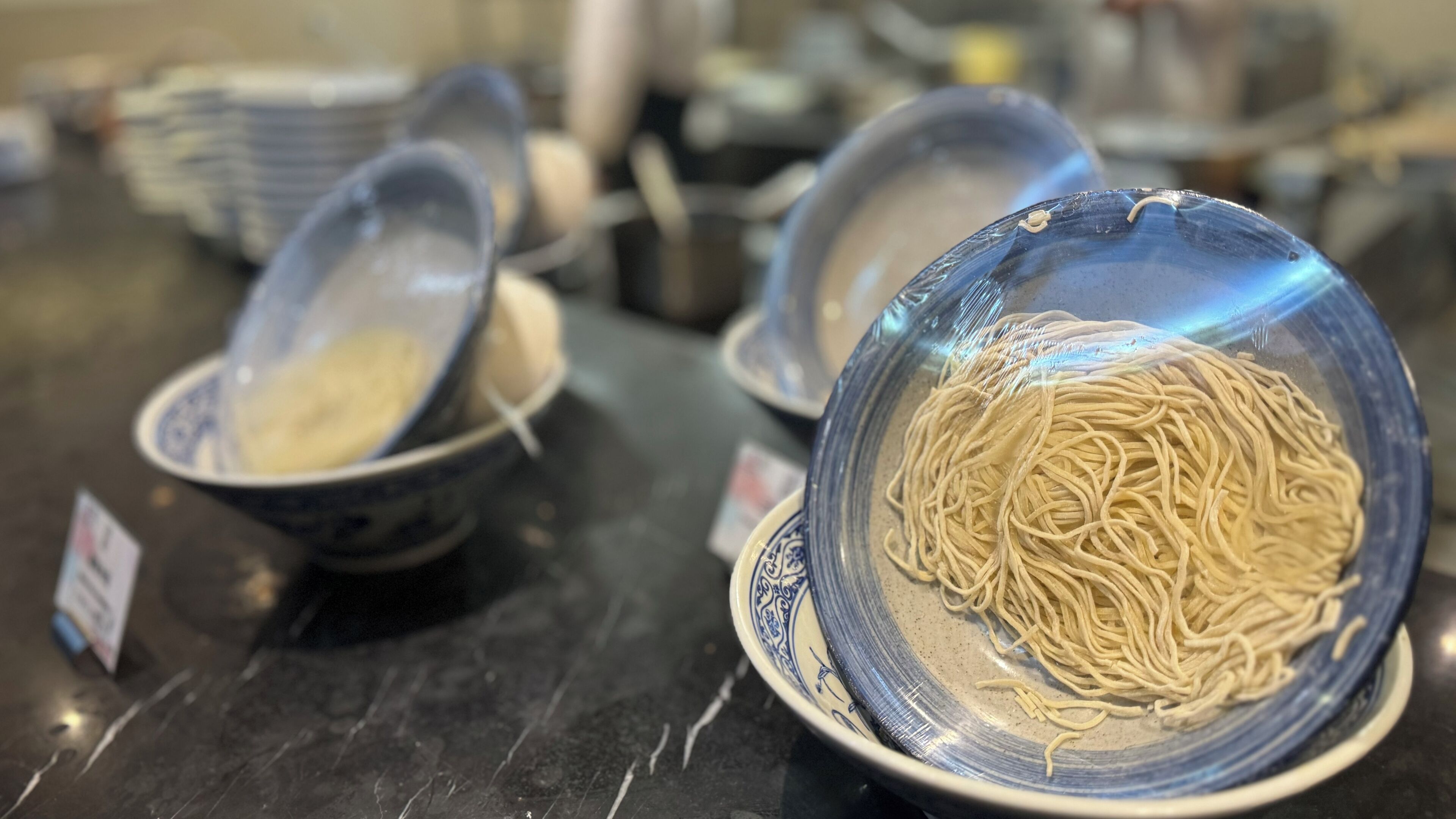 A bowl of noodles on a table with a blue and white pattern.