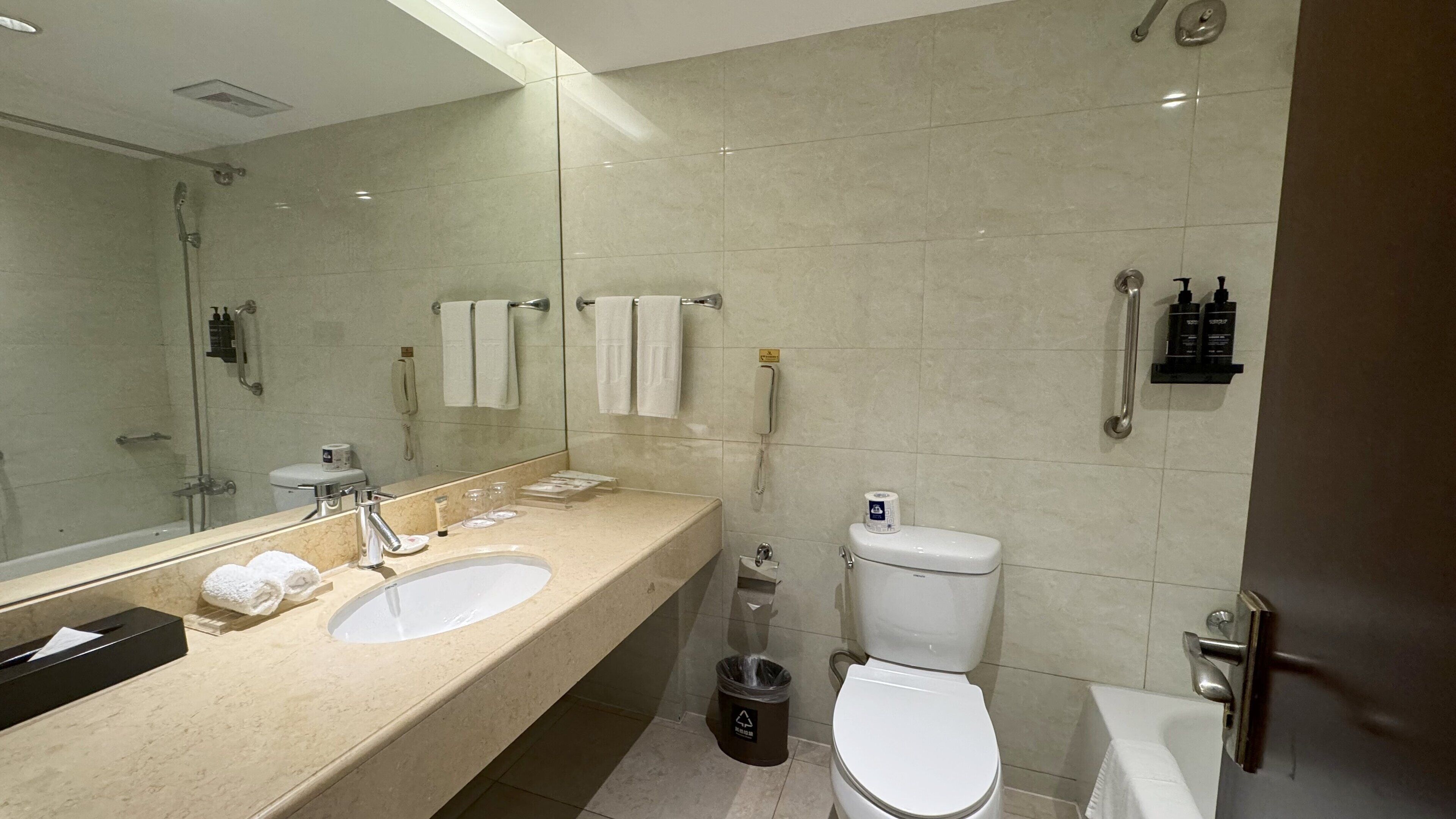 A modern bathroom with a large sink, mirror, toilet, and shower.