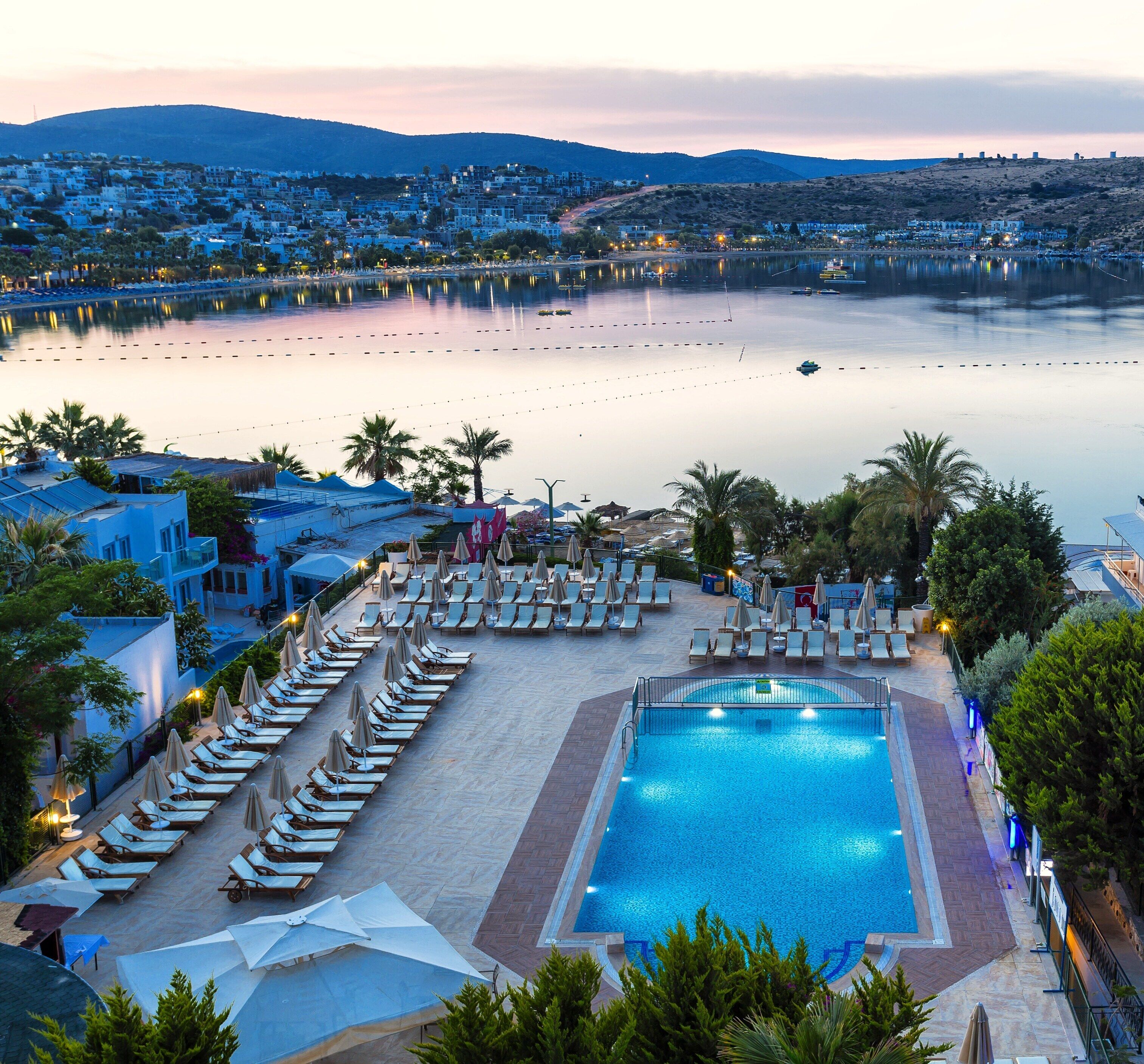 A resort with a swimming pool, lounge chairs, and umbrellas.