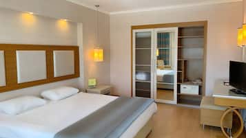Una habitación de hotel con cama, escritorio, televisor y armario con espejo.