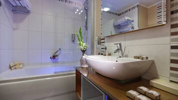 Ein modernes Badezimmer mit einer großen Badewanne, einem weißen Waschbecken und einem Spiegel darüber.