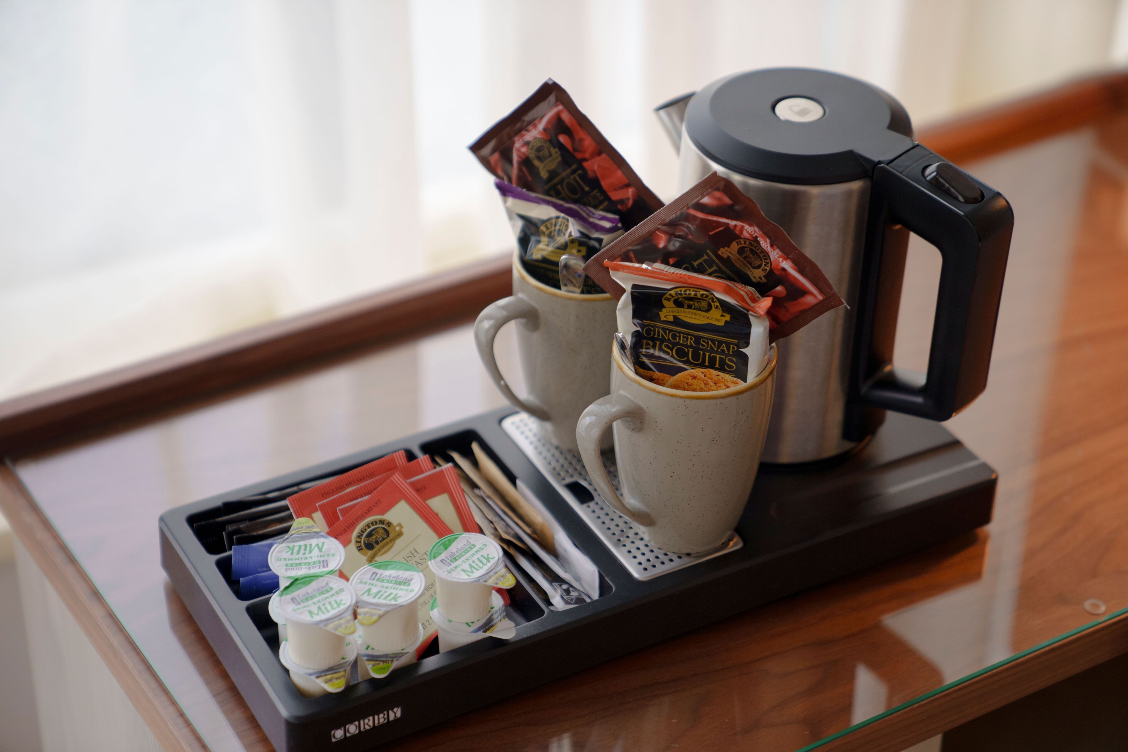 Een dienblad met een koffiezetapparaat, twee mokken en diverse etenswaren.