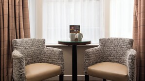 Two upholstered chairs with a textured fabric, a small round table with a glass top, and a brochure on the table. - The Wordsworth, Grasmere- The Inn Collection Group (Ambleside)