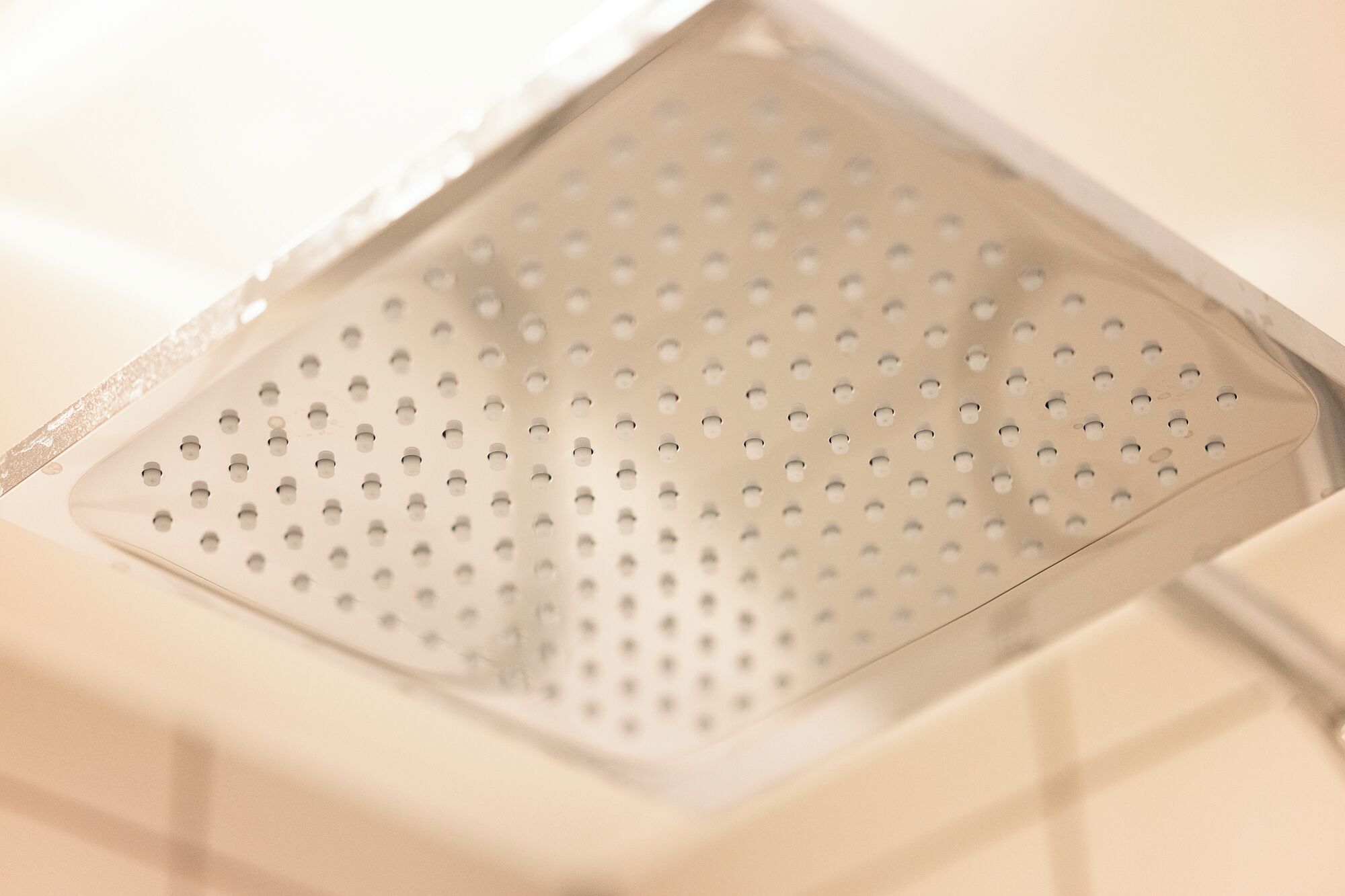 Gros plan d’un drain de douche muni d’une grille métallique perforée.