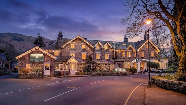 A stone building with a pub sign, multiple windows, and a paved road in front. - The Wordsworth, Grasmere- The Inn Collection Group (Ambleside)