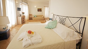 Una habitación de hotel con cama, escritorio, silla, sofá y televisor.