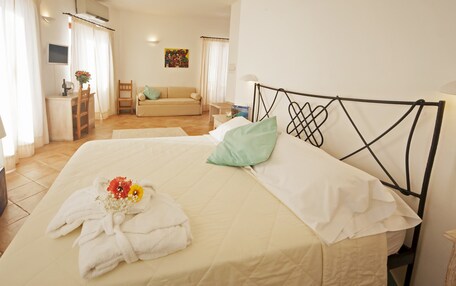A hotel room with a bed, a desk, a chair, a sofa, and a TV.