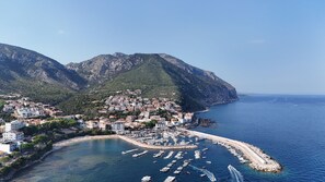 A coastal town with a marina, buildings, and a mountainous backdrop. - BUE MARINO HOTEL & ROOFTOP BAR (Dorgali)