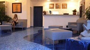 A lobby with a reception desk, seating area, and a patterned floor. - BUE MARINO HOTEL & ROOFTOP BAR (Dorgali)