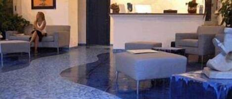 Um hall com balcão de recepção, área de estar e piso estampado.
