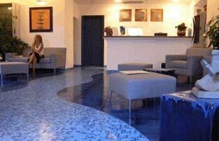 Un vestíbulo con mostrador de recepción, zona de estar y suelo estampado.