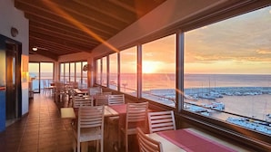 Un restaurante con vista al mar y barcos al atardecer.