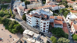 Un hotel de varios pisos con balcones, ubicación frente a la playa y zona de estacionamiento.
