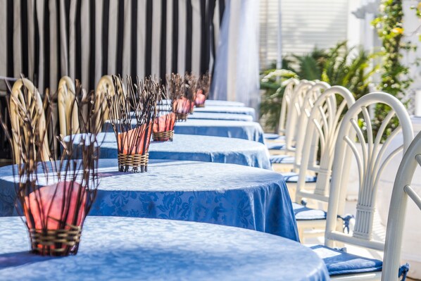 A row of tables with blue tablecloths and white chairs, each with a candle holder. - Hotel Diamond (Riccione)